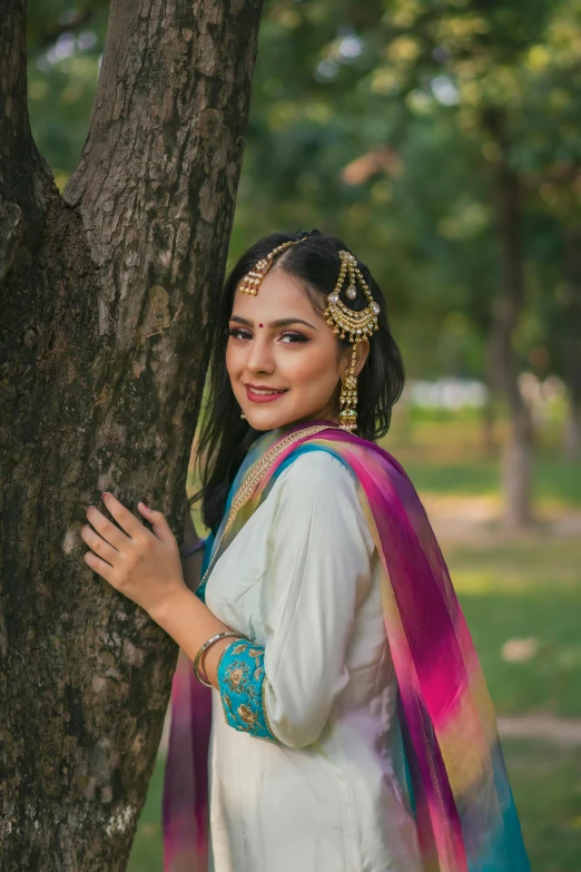 a woman standing under a tree in an indian costume