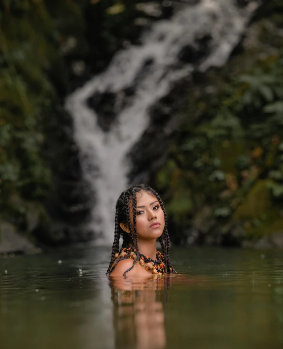 a woman swims in a river near a waterfall