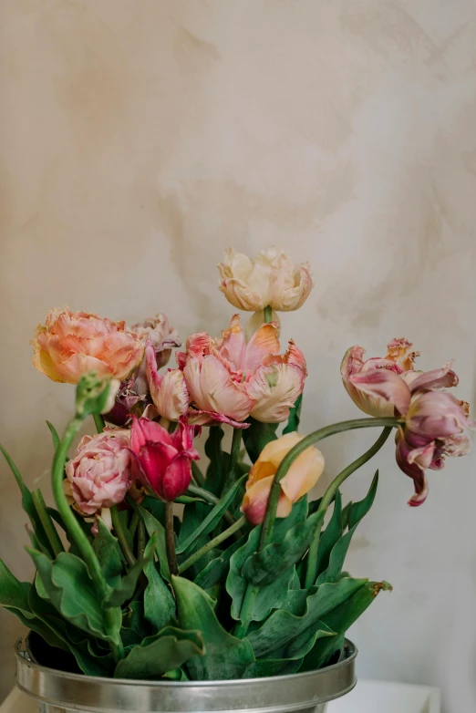 a metal vase holds a variety of flowers