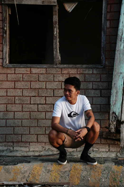 a person crouching down in front of a brick building