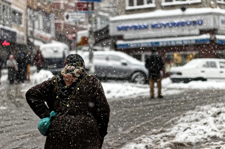 a person in a hat standing on a snowy street