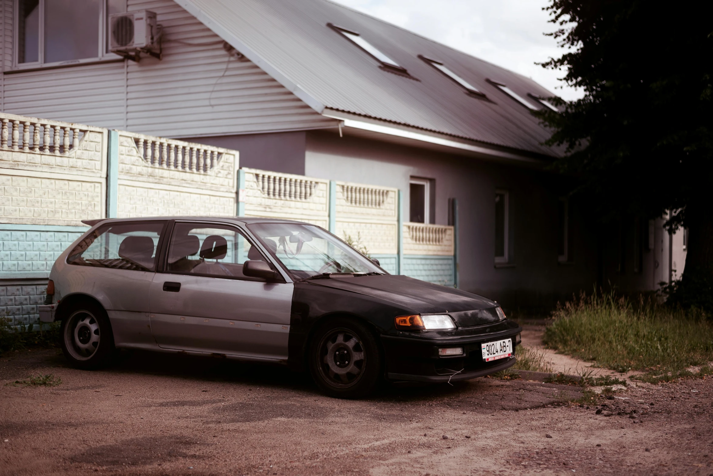 an old car parked next to a house in front of the gate