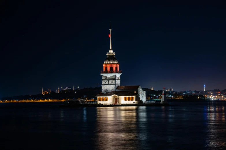 large building with red and white on the top and lights reflected in water