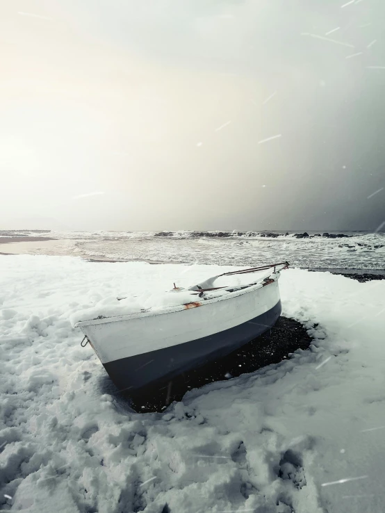 a white boat sitting on top of snow covered ground