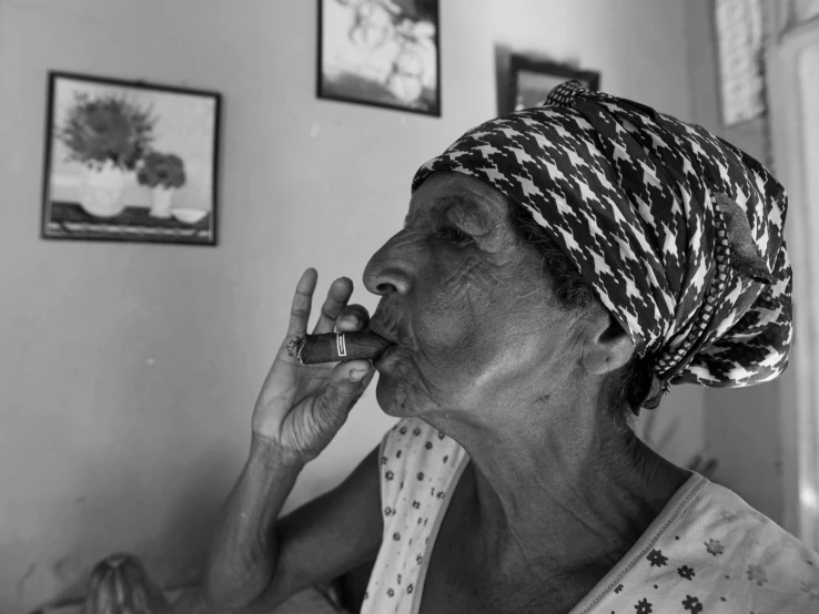 a lady in a headscarf blowing on her cigarette