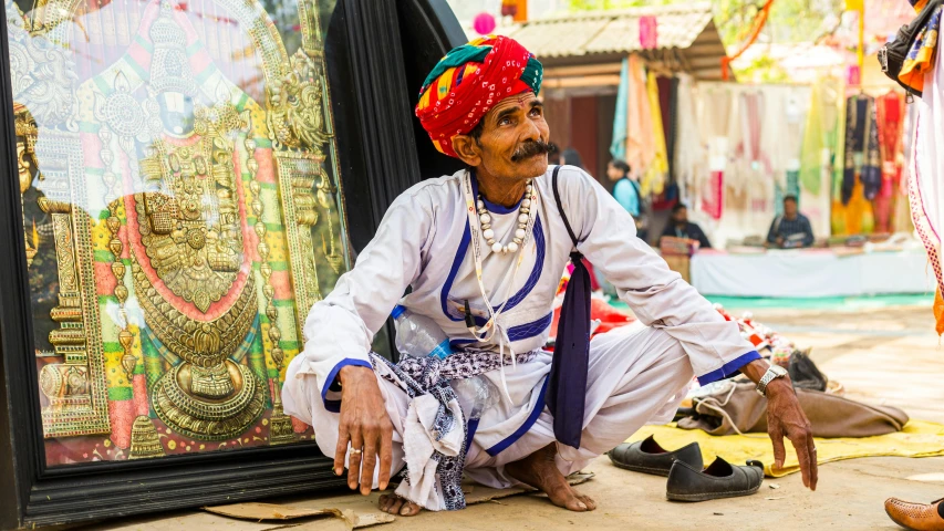 a man sitting on the ground in front of several colorful art