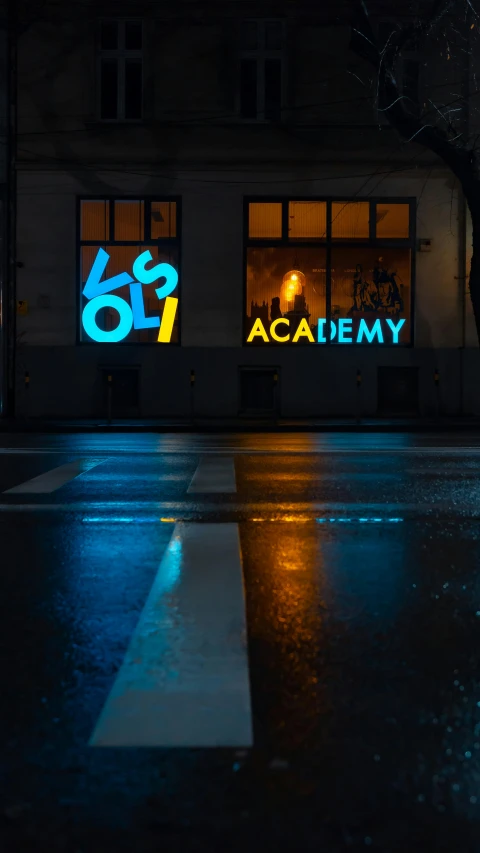 a dark street and sidewalk with an illuminated sign on the side of the street