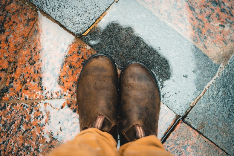 a person's feet in brown boots with their legs crossed