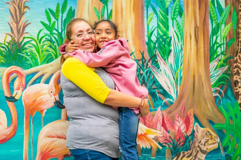 the woman is hugging her daughter in front of a mural