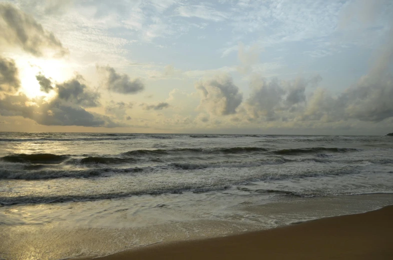 an ocean with waves and clouds and a beach