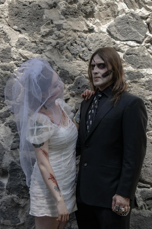 the bride with makeup on her face and skull make - up poses next to the groom