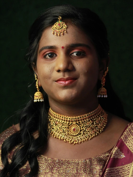 an indian woman with big gold jewelry poses for the camera