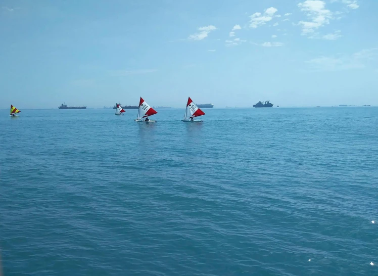 three small sailboats traveling across the ocean together