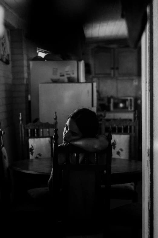 a little boy sitting at a table in a kitchen