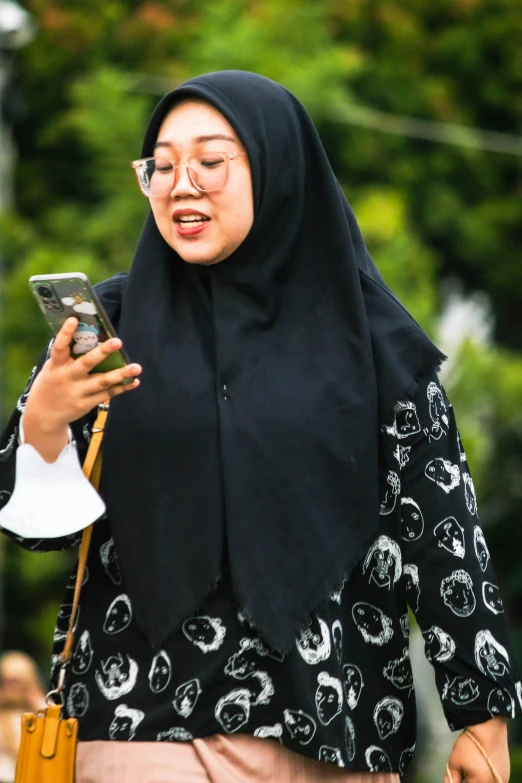 a woman in hijab looks at her cell phone