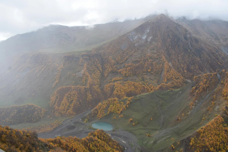 the mountains are covered in trees with a pond