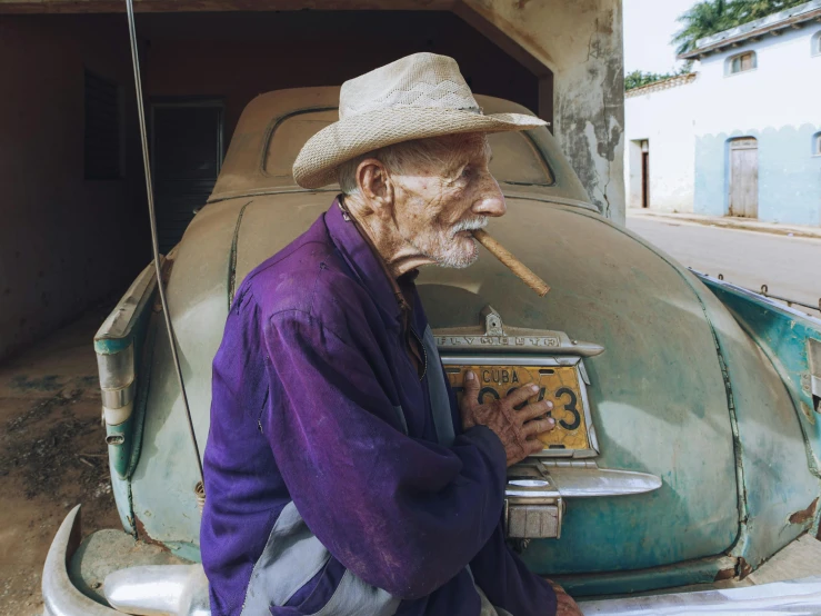 an old man smoking while sitting on the side of a road