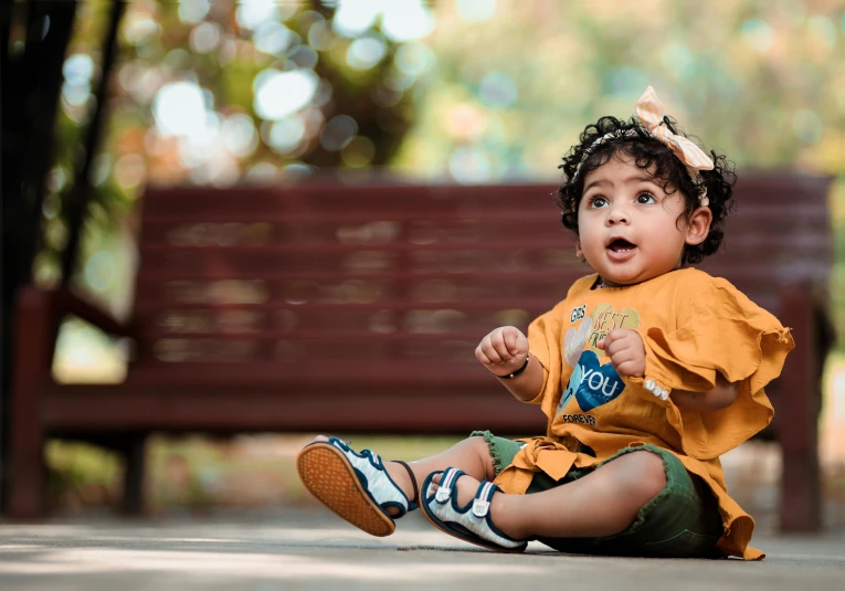 the child is sitting on the ground next to a bench