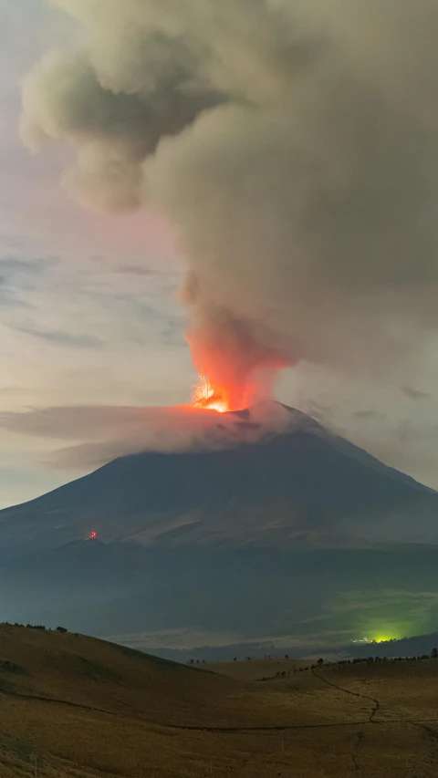 a mountain with smoke coming out of the top and light on it