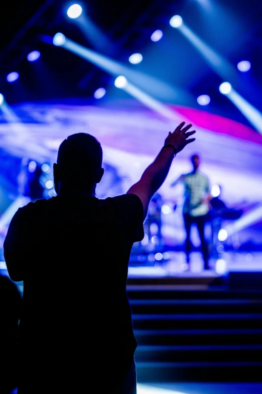 silhouetted figure standing in front of a brightly lit stage