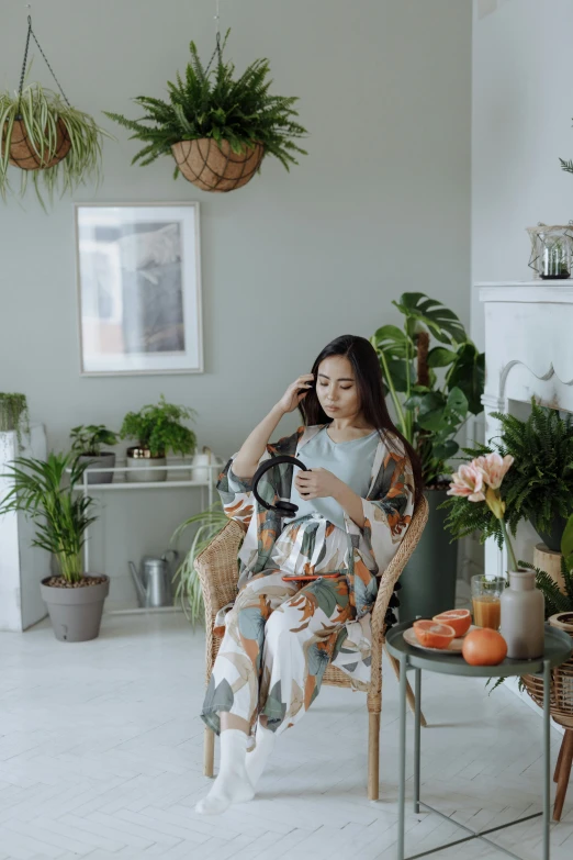 a young woman sitting in a chair next to potted plants