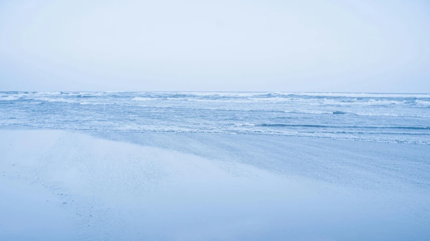 a lone person walks on the beach towards the ocean