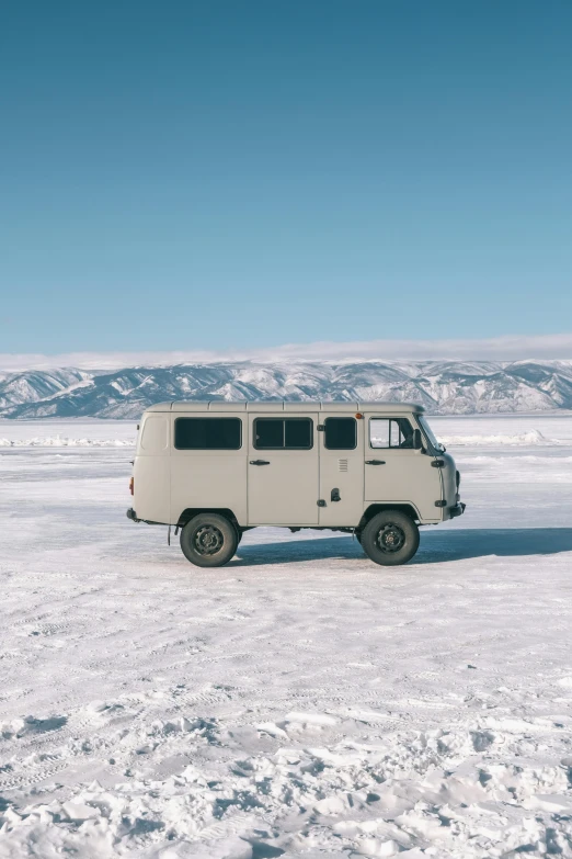 a car sitting in the snow with mountains in the background