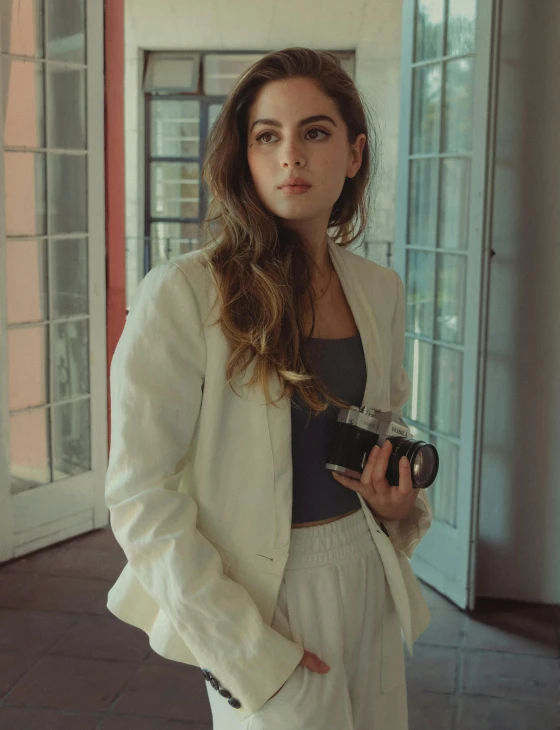 young lady wearing a white jacket, holding a camera