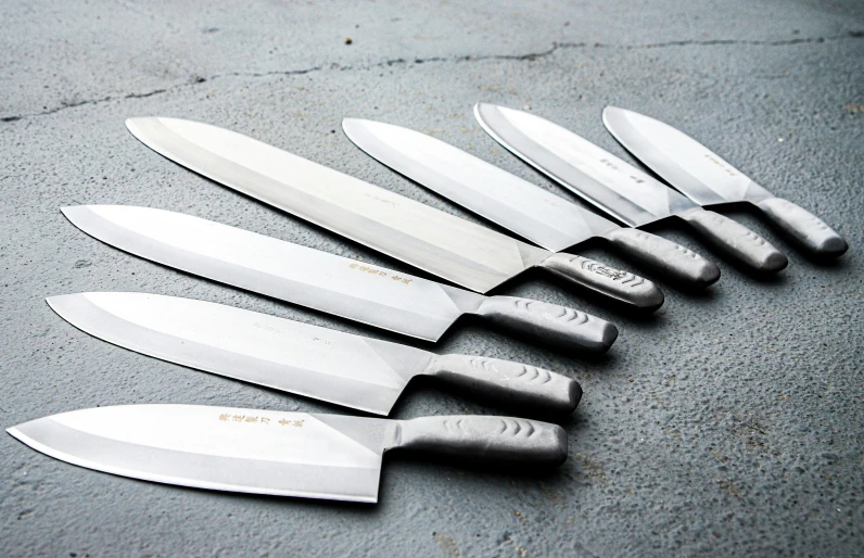 many knives lie lined up together on the table