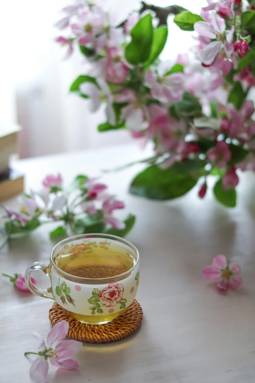a cup of tea sits on a tray with pink flowers