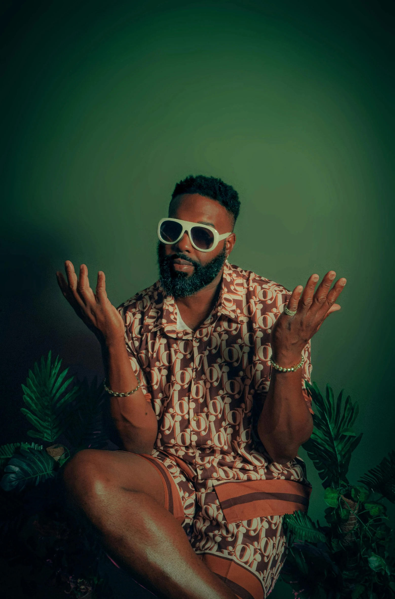 a bearded man wearing shades with palm trees behind him