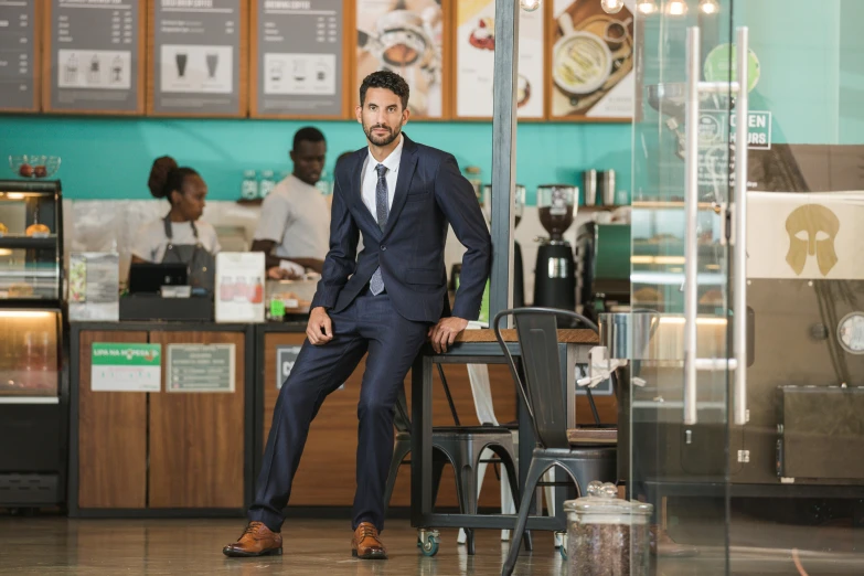 a man wearing a suit standing at a counter of a cafe