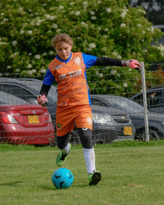 soccer player in orange uniform about to kick a ball