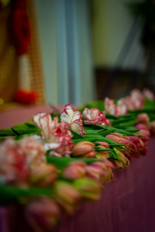 several flowers on the table along side of a white and pink curtain