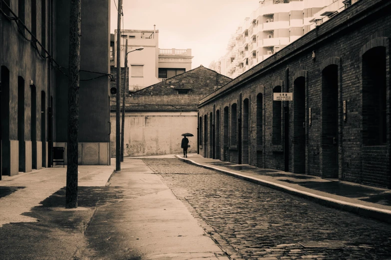 a man stands alone on a cobblestone street in an alleyway