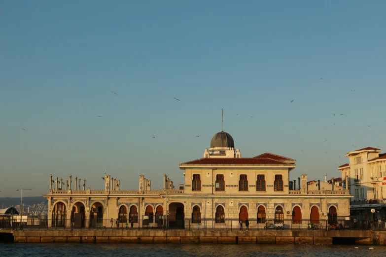 a building overlooking a large body of water with people standing nearby