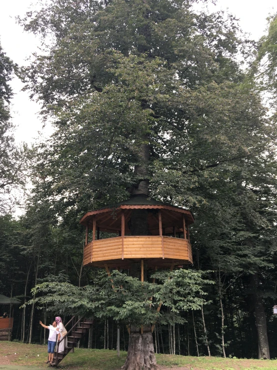 a couple is posing in front of a large tree house