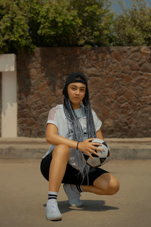 a woman sitting with a soccer ball outside