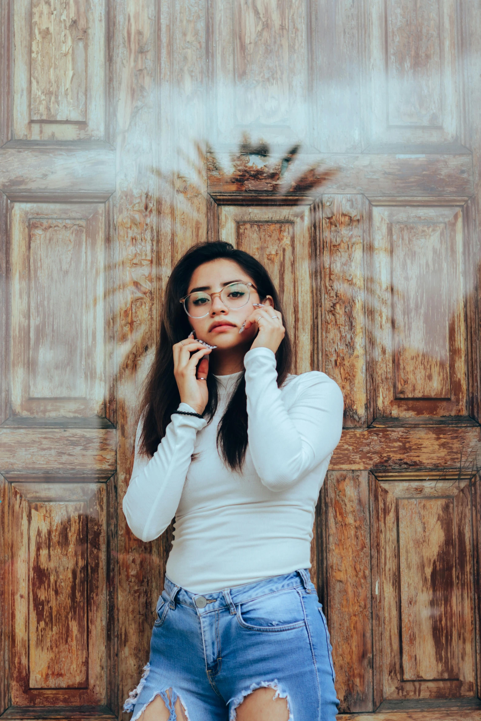 a woman leaning on a wooden door with one hand up to her face