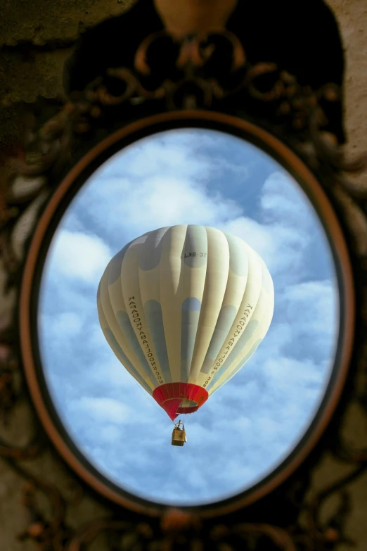 the reflection in the mirror shows a  air balloon flying in the sky