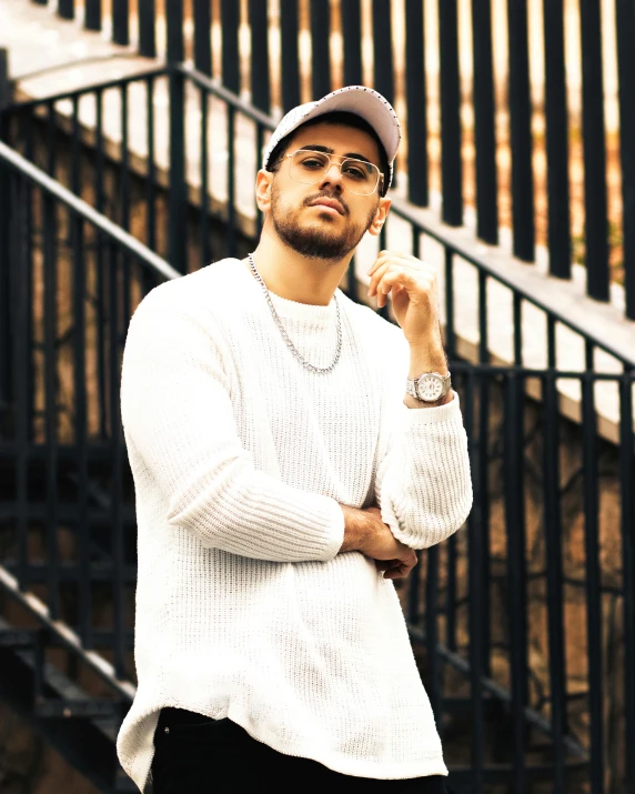 a man wearing a hat and shirt poses in front of a stair case