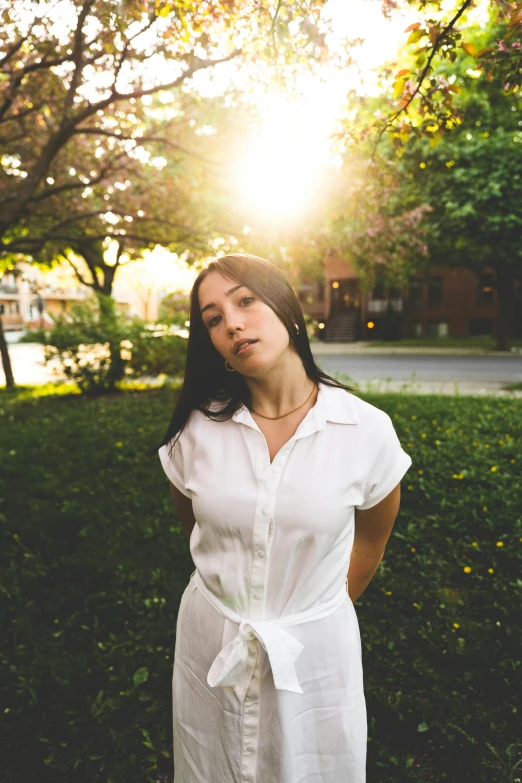 a woman wearing a white dress standing in the sun