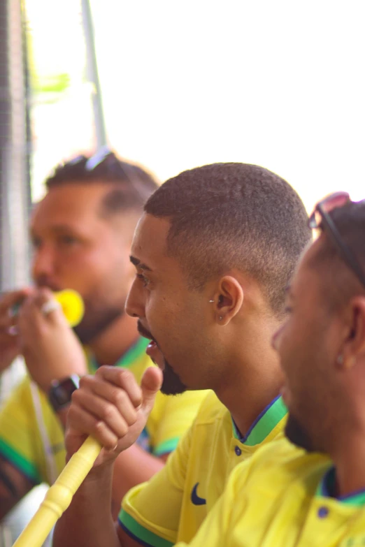 several people are in yellow shirts while one of them is holding a baseball bat