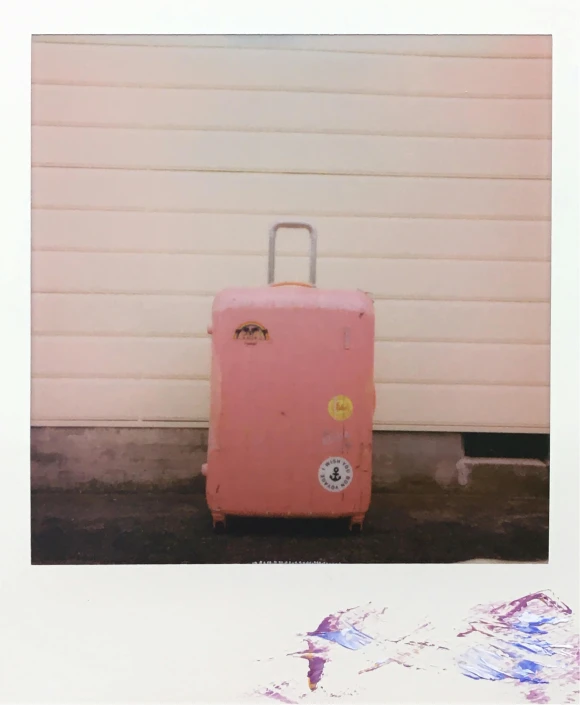 an old fashioned pink suitcase sitting outside a garage door