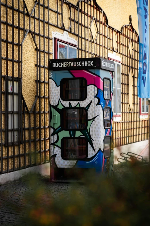 a graffiti - covered box is standing outside in front of a wall