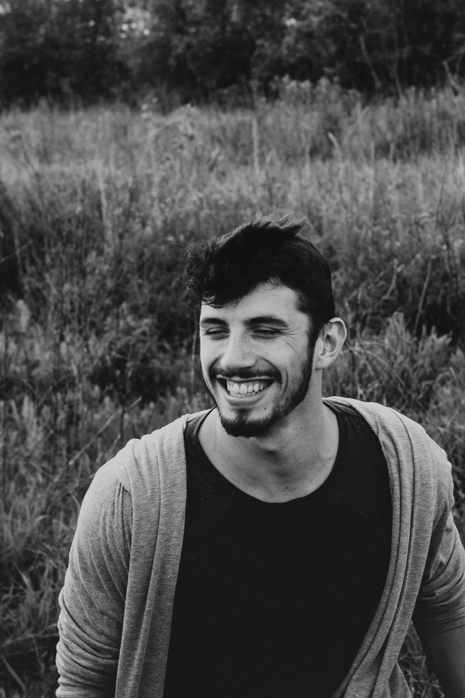 a smiling man sitting in a field of tall grass