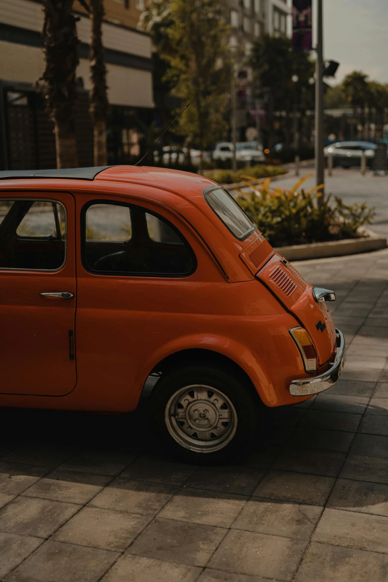 an orange car parked along a street with tall buildings