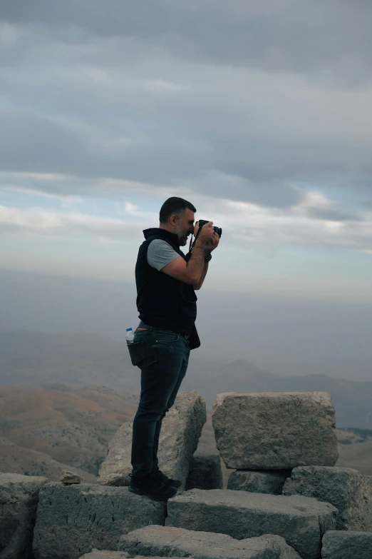 a man with camera on top of rock formation