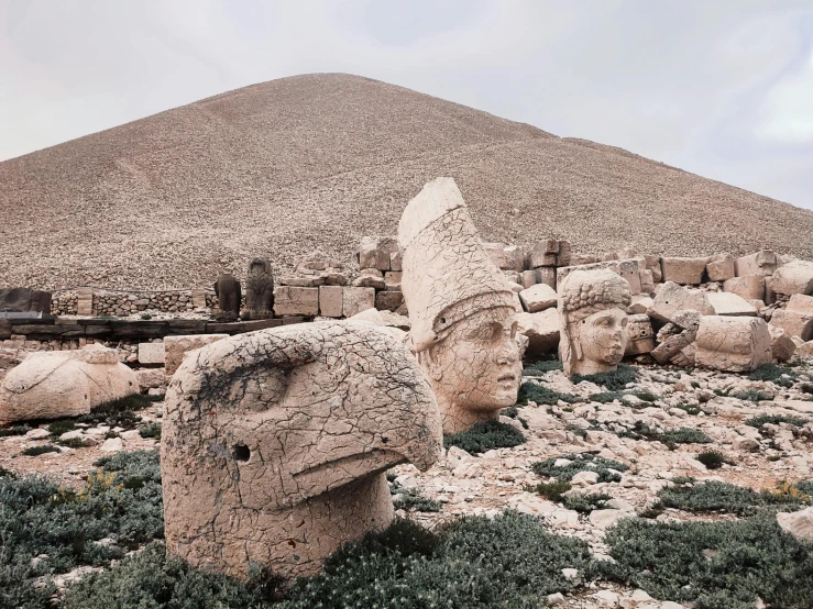 ancient statues with heads made out of rocks are shown at the base of a pyramid