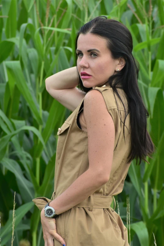 a woman standing in a corn field wearing an all brown dress